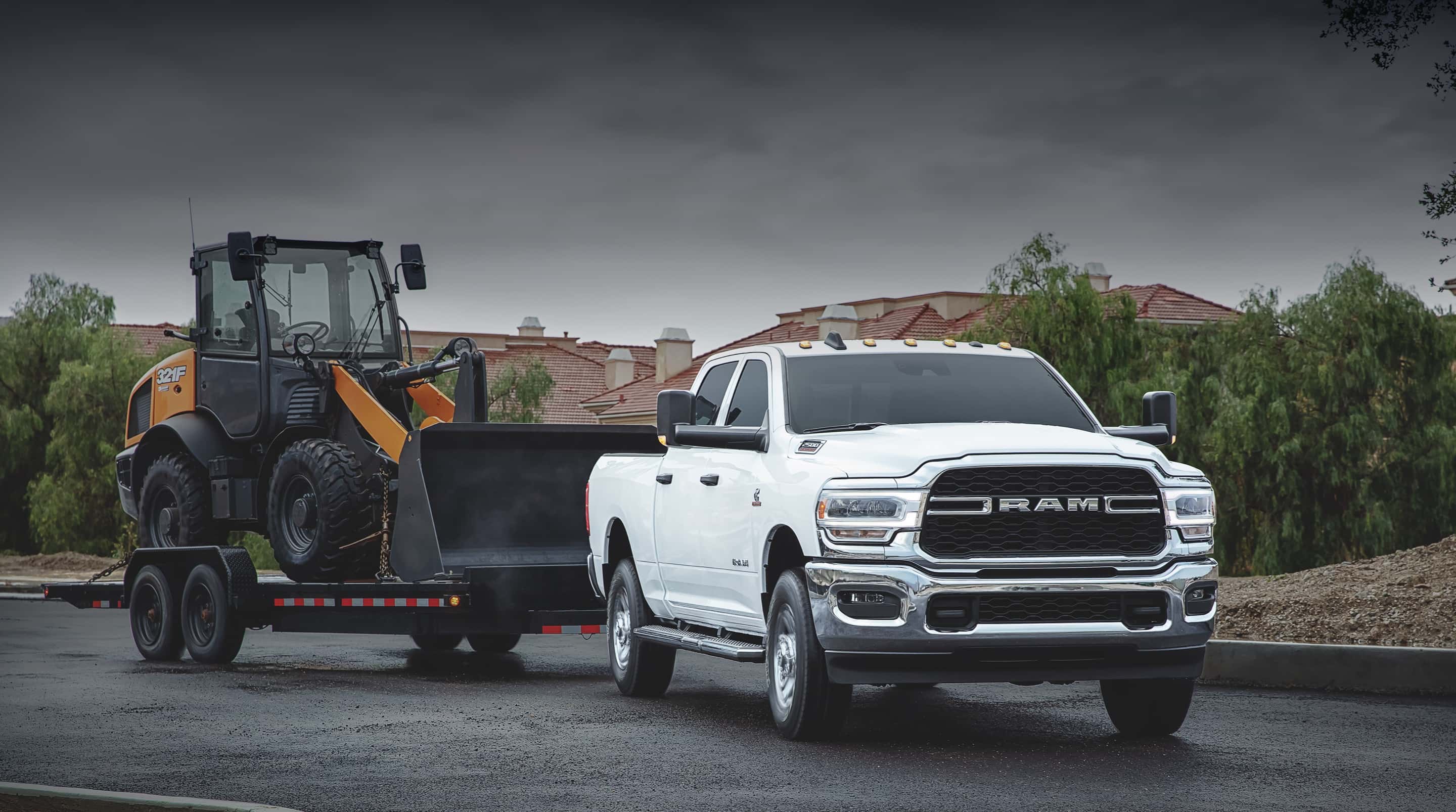 Ram 2500 pickup truck towing a deckover equipment trailer loaded with a Case wheel loader in Lorain, Ohio